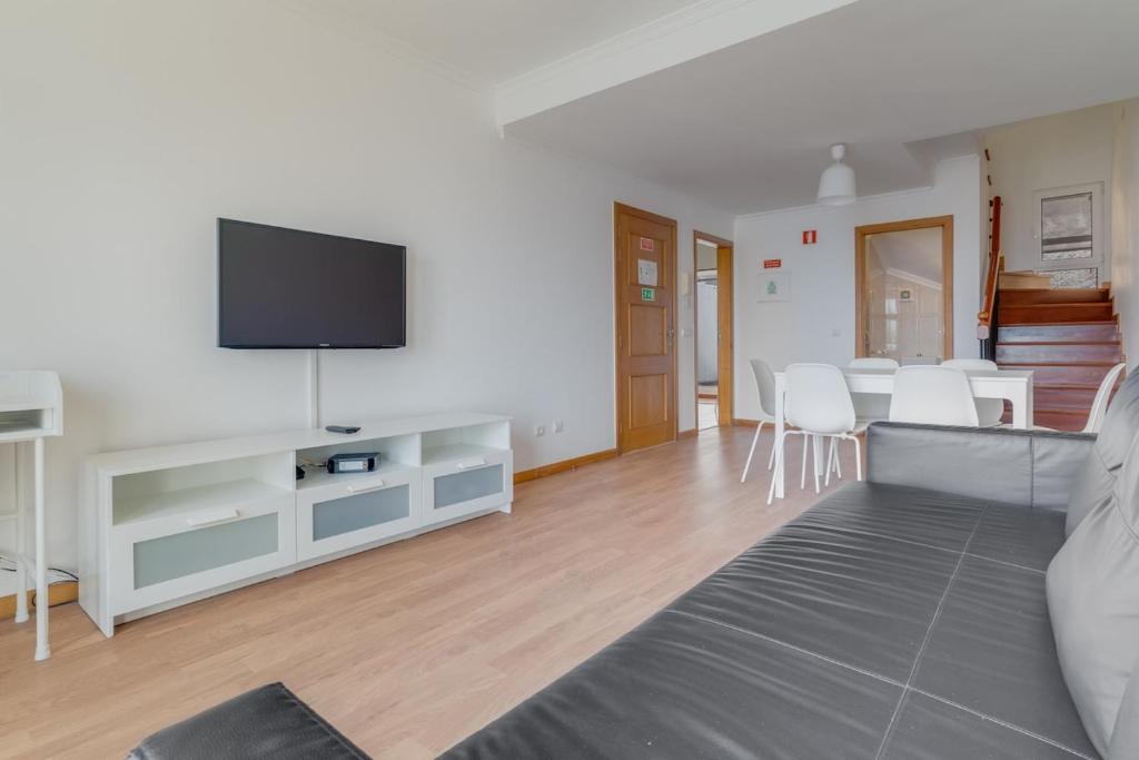 a living room with a couch and a flat screen tv at Esfera I Calm Stay With Parking & Workspace in Caniço