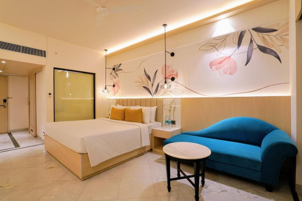 a hotel room with a bed and a blue couch at Hotel Le Jardin in Erode