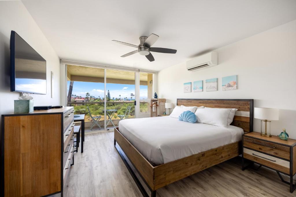 a bedroom with a bed and a flat screen tv at Beachside Maui studio with pool & hot tub access in Wailea
