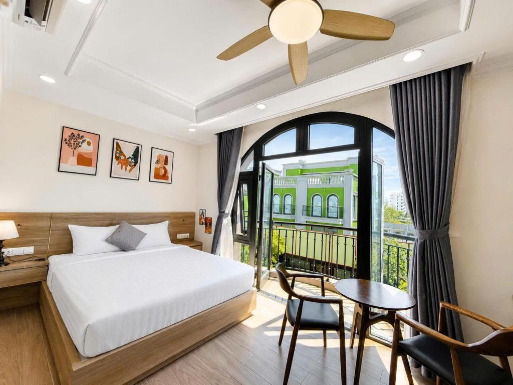 a bedroom with a bed and a table and a window at Apple Phu Quoc Hotel & Restaurant in Phú Quốc