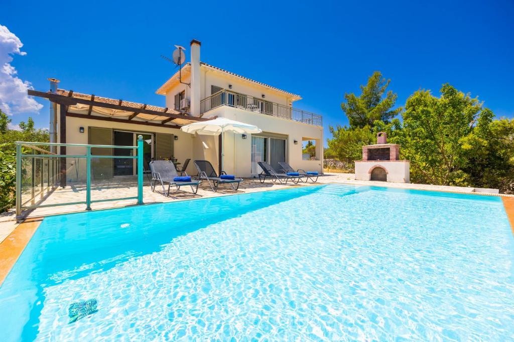 a villa with a swimming pool in front of a house at Villa Eudora in Tsoukalades