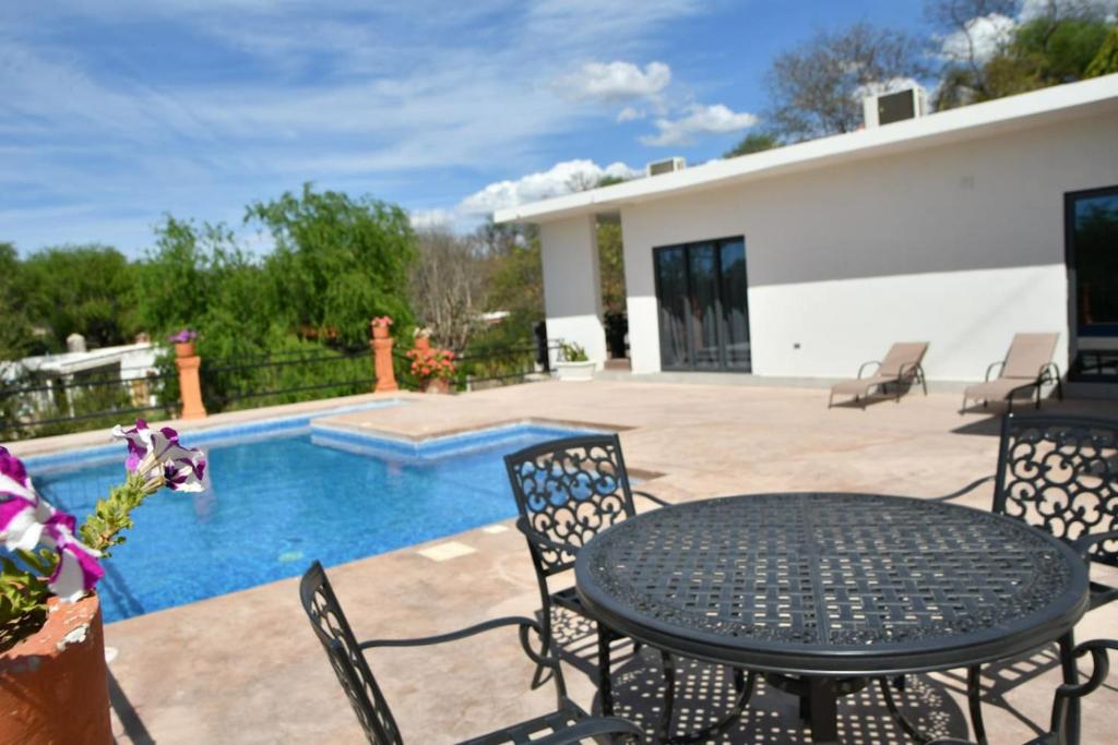 a patio with a table and chairs next to a pool at Casa de Cuatro Vientos in Álamos
