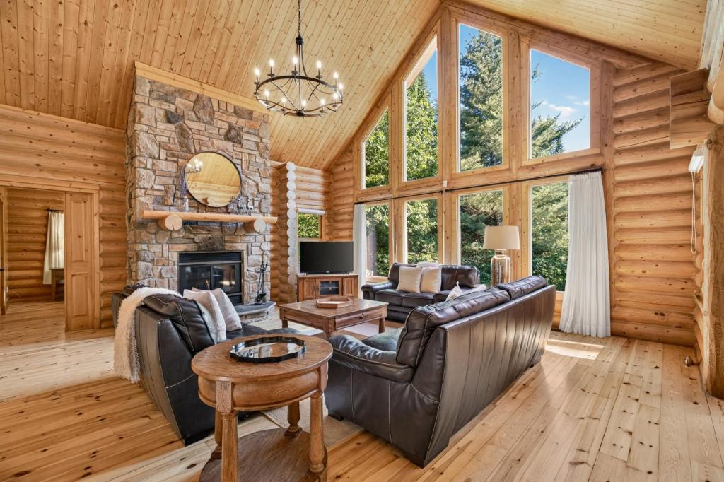 a living room with leather furniture and a stone fireplace at Fiddler Lake Resort - Deer 47 in Mille-Isles