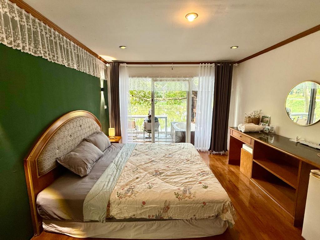 a bedroom with a bed and a green wall at Ban Mali Cafe & Riverside Stay in Ban Chang