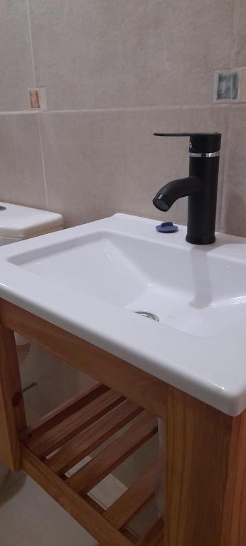 a white bathroom sink with a black cup on it at El Tropezon cabaña in Resistencia