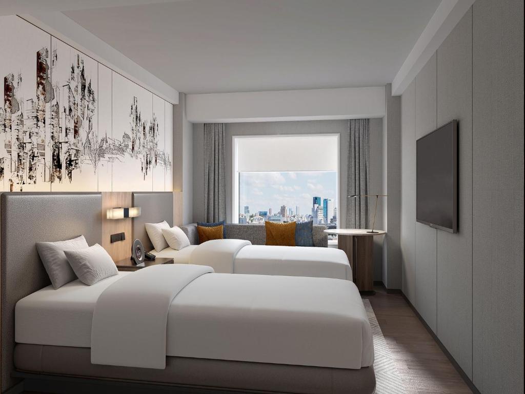 a hotel room with two beds and a window at Hotel Crown Palais Kitakyushu in Kitakyushu