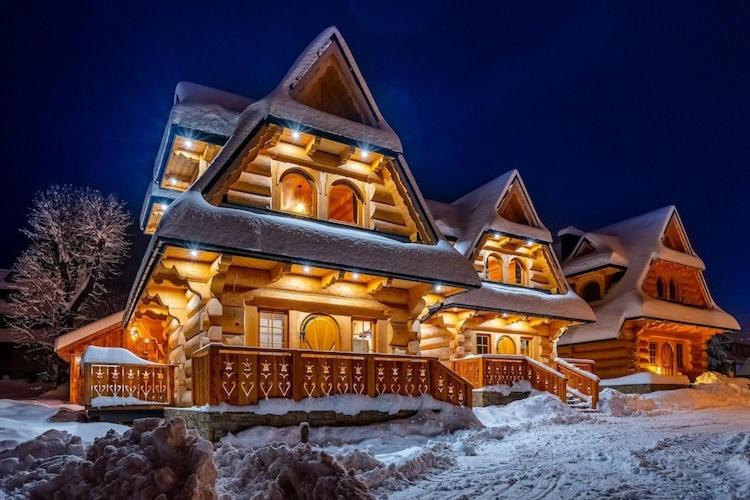 a log cabin in the snow at night at A large mountain-style house with a spa area in Murzasichle