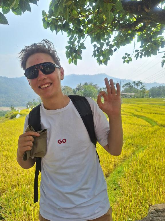 a man wearing sunglasses and a backpack holding up a peace sign at Heritage Haven in Kandy