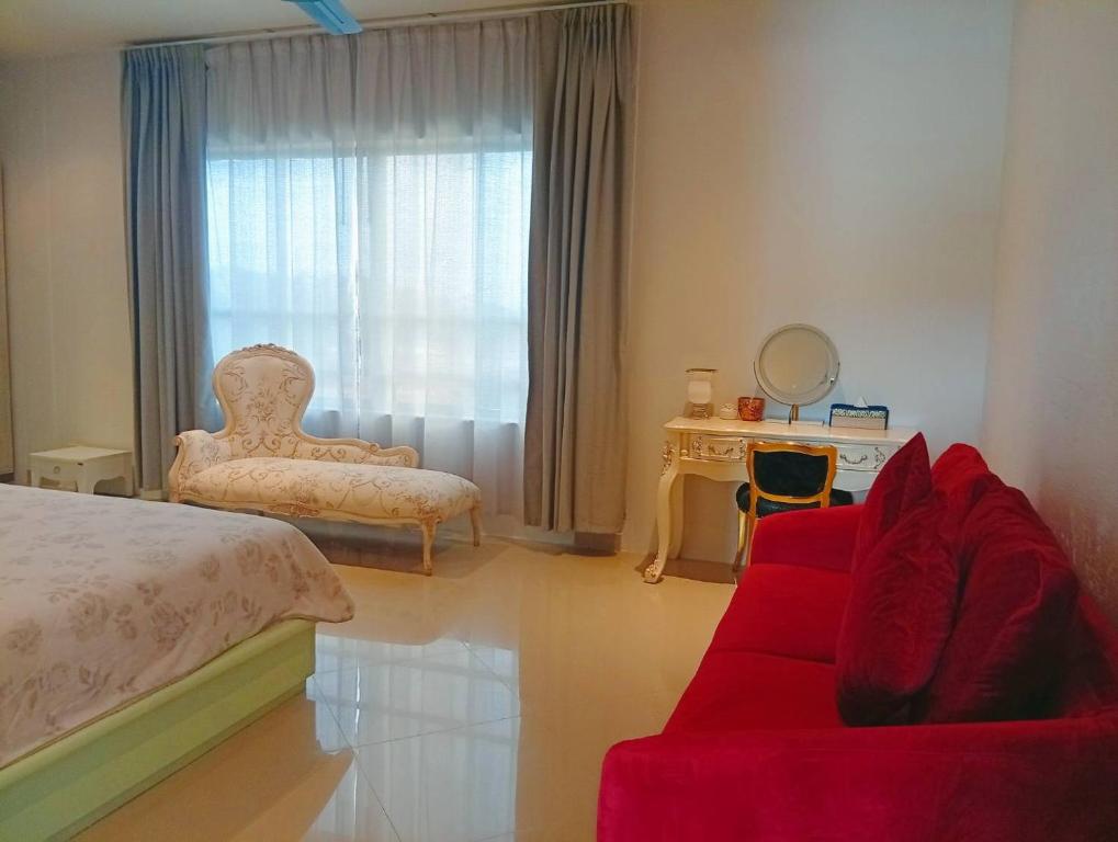 a bedroom with a red couch and a chair and a window at Klong Muang Beach Apartment in Klong Muang Beach