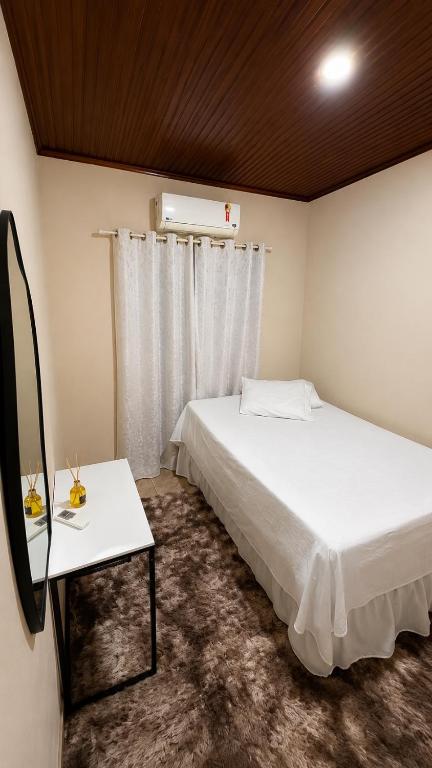 a bedroom with a white bed and a window at Cantinho aconchego in Naviraí