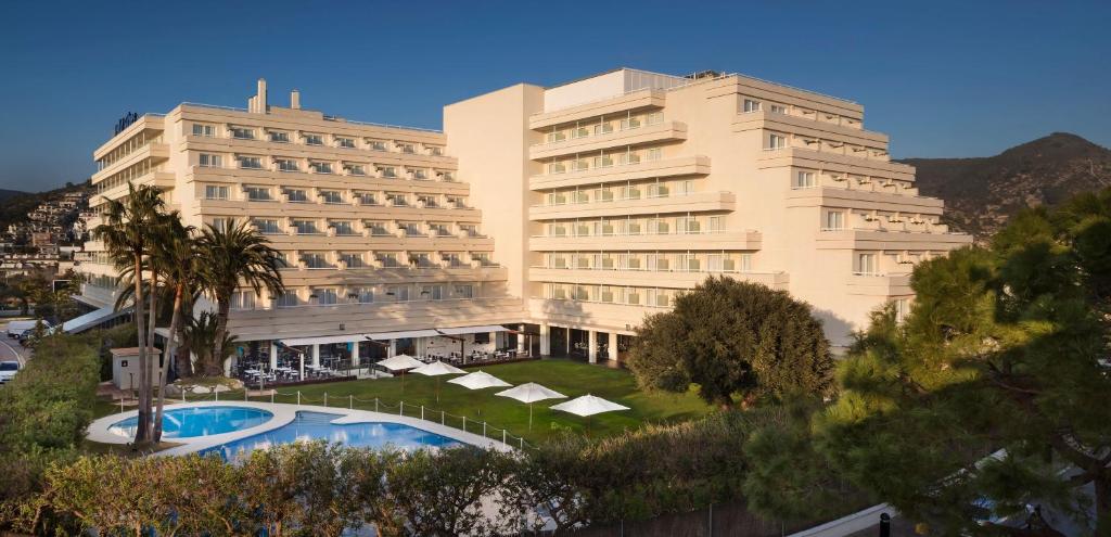 a large white building with a pool in front of it at Meliá Sitges in Sitges
