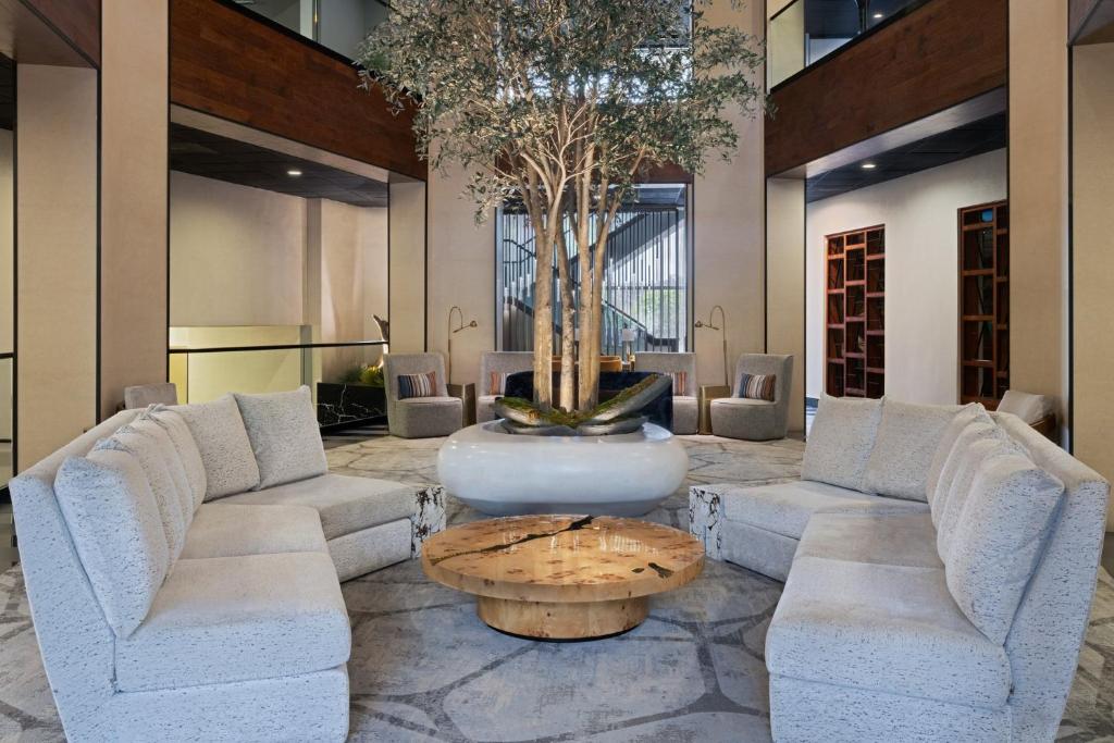 a lobby with couches and a table and a tree at voco Laguna Hills by IHG in Laguna Hills