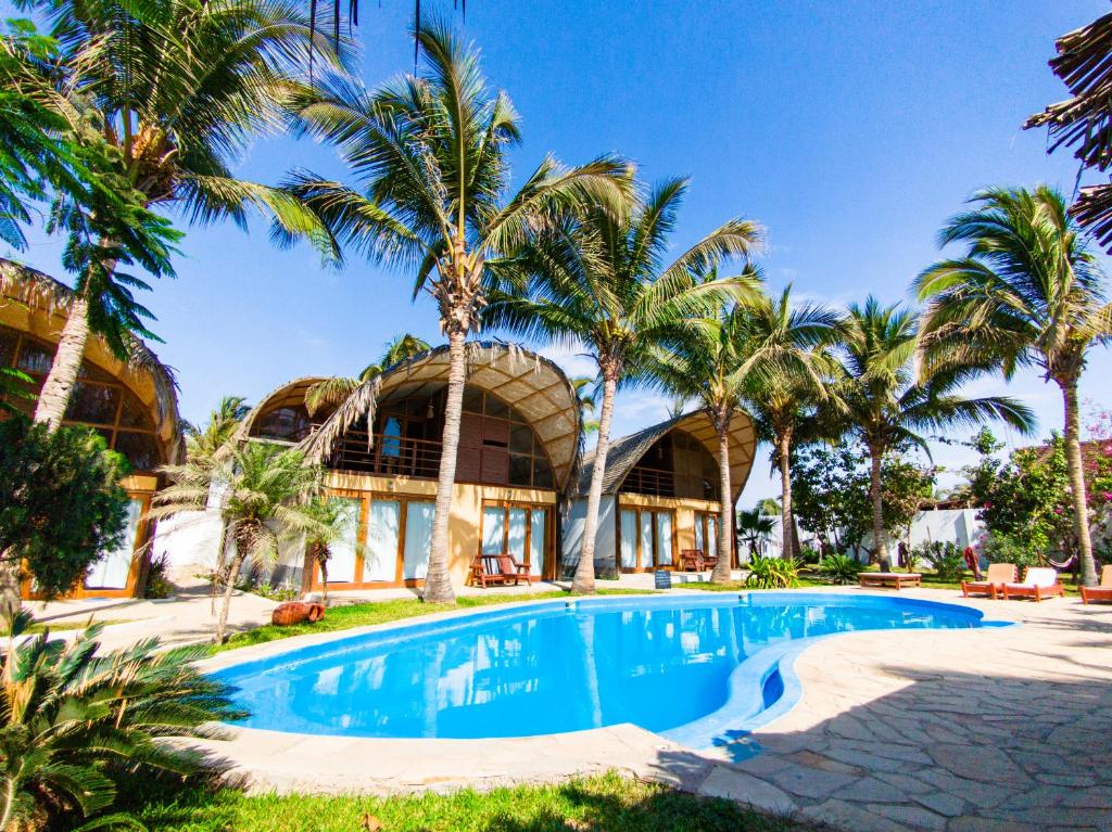 an exterior view of a resort with a swimming pool and palm trees at Kites Mancora in Máncora