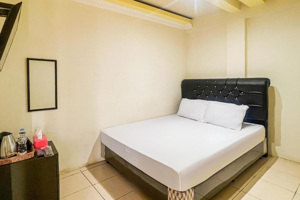 a bedroom with a bed with a black headboard at Kings Hotel Dieng RedPartner in Diyeng