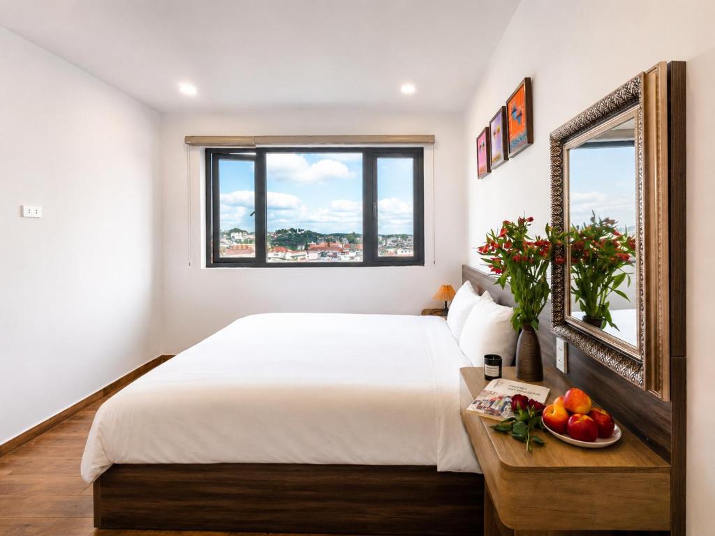 a bedroom with a bed and a bowl of fruit on a table at Laimeront Hotel Dalat Vietnam in Da Lat