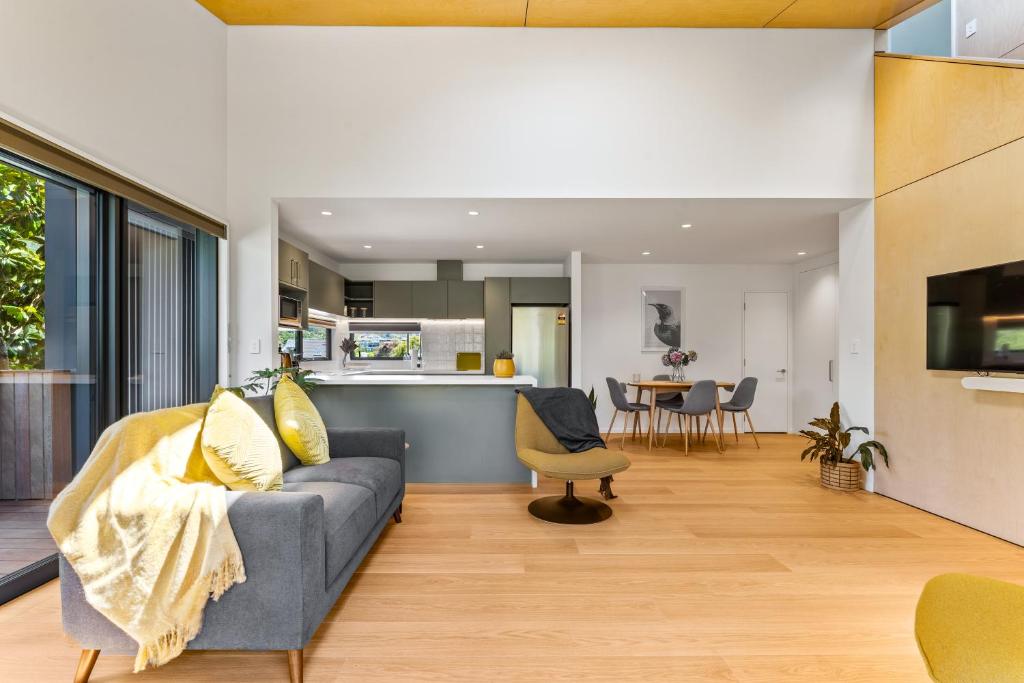 a living room with a couch and a kitchen at Totara tree house in Nelson