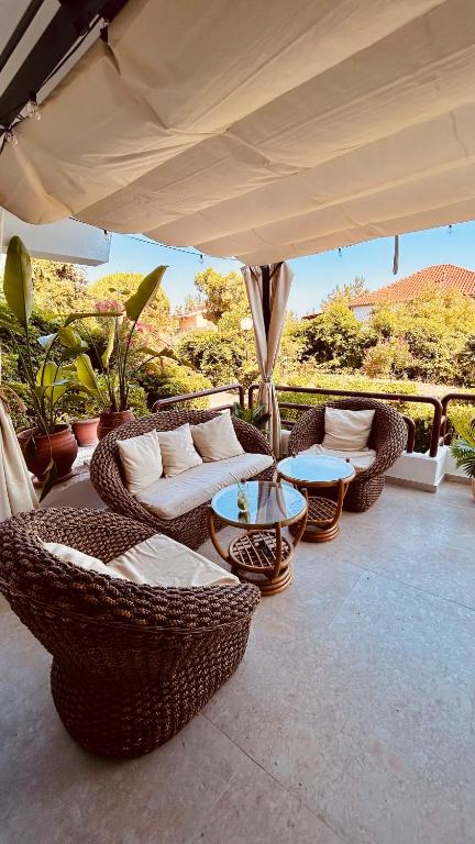 a patio with wicker chairs and tables under an umbrella at Sigma Exotic Palio Beach Apartment in Paleo Tsifliki