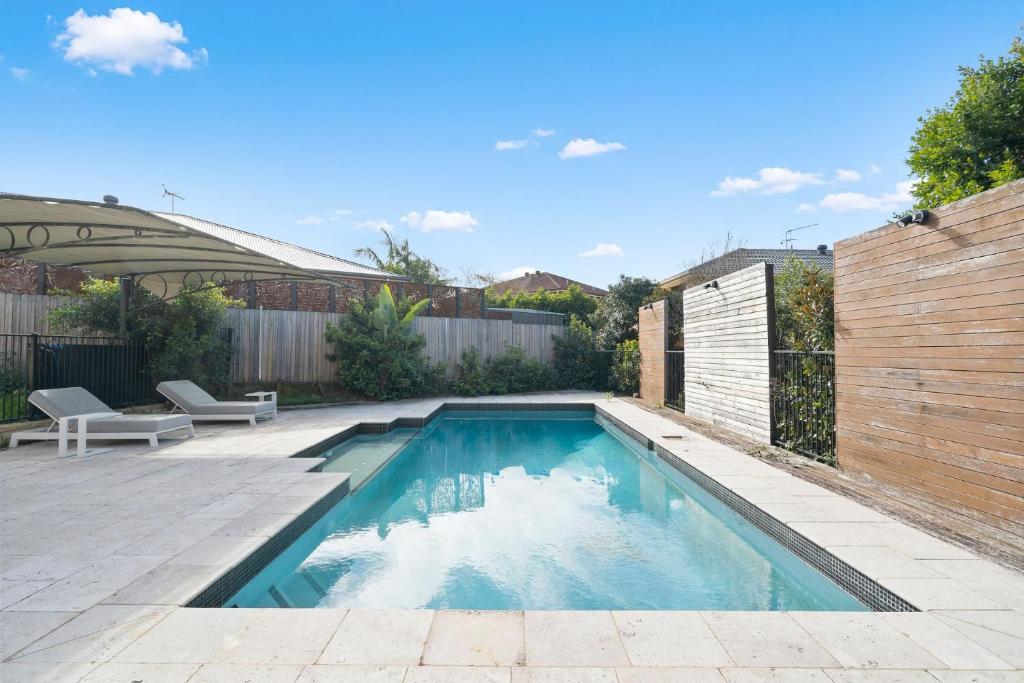a swimming pool in a backyard with a fence at Drumbern Pool House Macquarie Links in Ingleburn