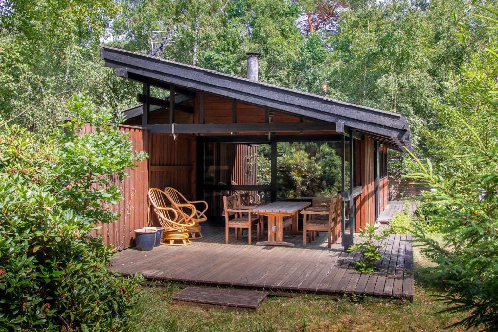a cabin with a wooden deck with a table and chairs at Architectdesigned 1976 Summer House Near Beach in Store Fuglede