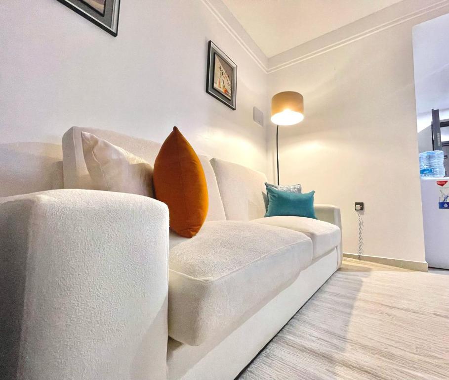 ein Wohnzimmer mit einer weißen Couch und Kissen in der Unterkunft Sunset Stays near UN, Two Rivers & Village Market with Gym & Pool in Ruaka