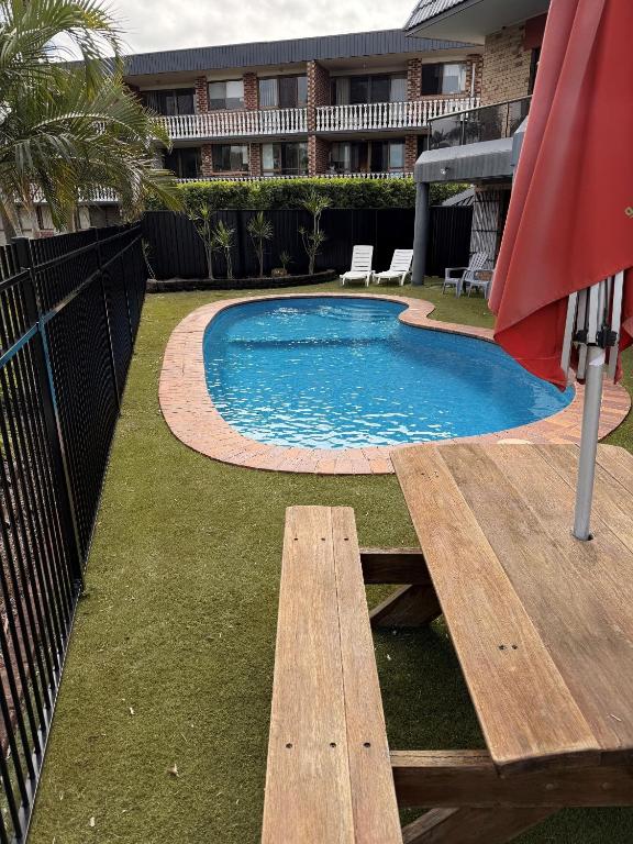 a swimming pool with a bench and an umbrella at Bribie Waterways Motel in Bongaree