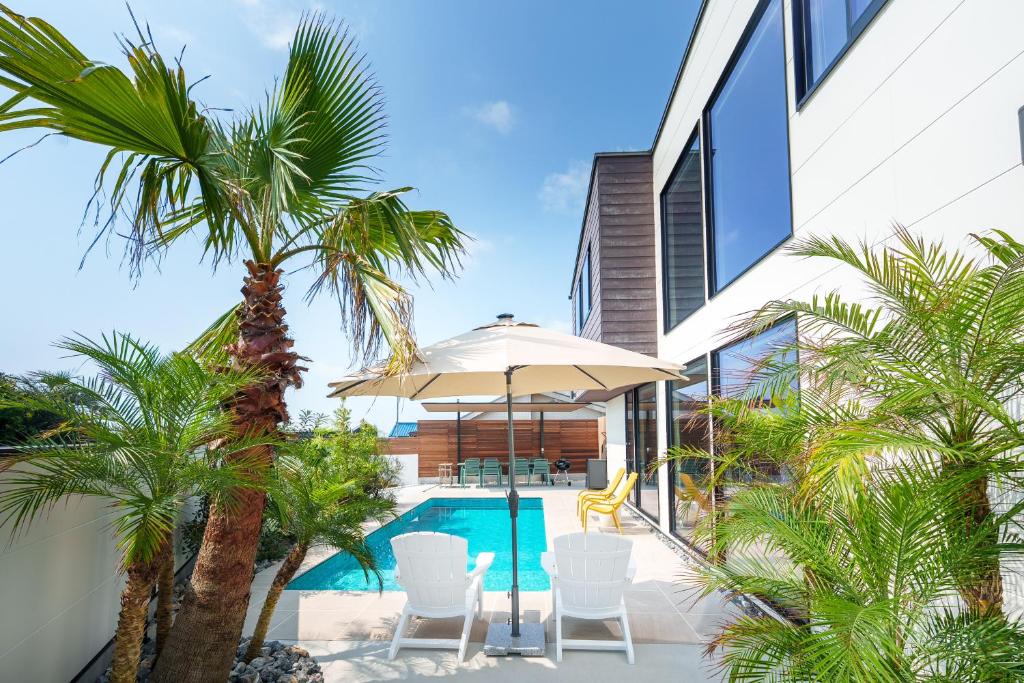 an external view of a villa with a swimming pool and palm trees at 2026年8月新築,海直結!!ビーチフロント,オーシャンビュー,プール,サウナ付きヴィラ---Taito Pool EDGE--- in Chōjamachi
