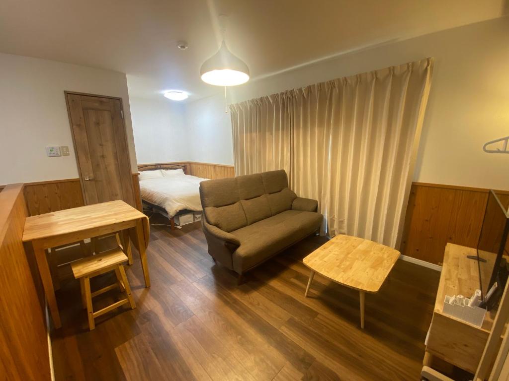 a living room with a couch and a bed at Bise House in Motobu