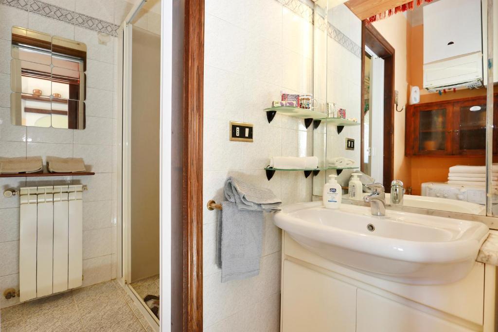biała łazienka z umywalką i lustrem w obiekcie Oltrarno Home Silvia Florence we Florencji