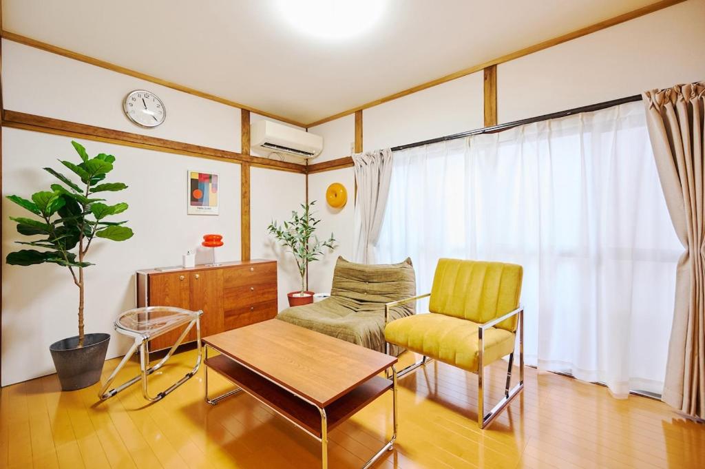 a living room with a table and a chair at Kokonimo Niiza in Niizo