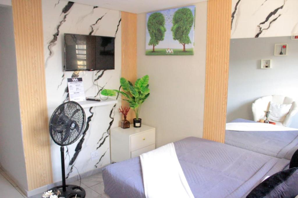 a bedroom with a bed and a fan in a room at Viva Guest House in Trevallyn