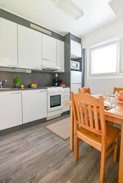 a kitchen with white cabinets and a wooden table at Helmiapartments Sotkamo in Sotkamo