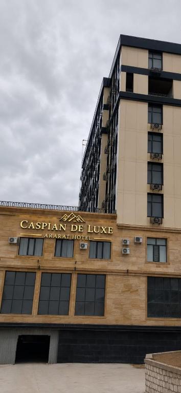 a building with a sign on top of it at Caspian Deluxe Apart Hotel in Aktau