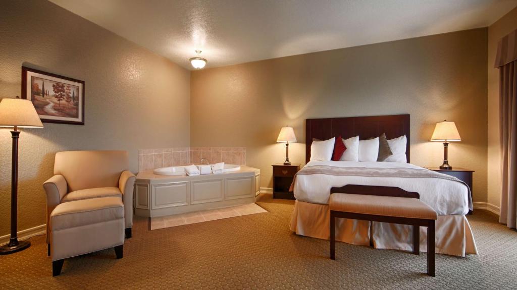 a bedroom with a bed and a chair and a tub at Best Western Plus Bayshore Inn in Eureka