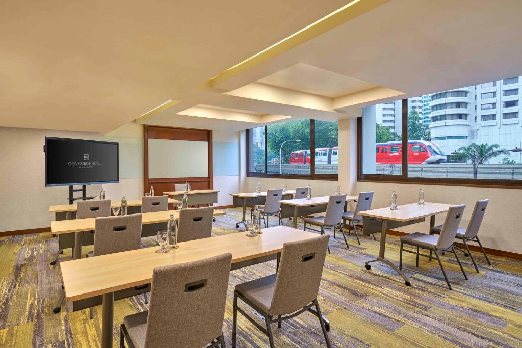 A windowed meeting room offers classroom-style tables and a presentation display.