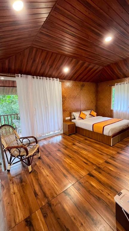 a bedroom with a bed and a chair in a room at Cave Valley Wayanad in Ambalavayal