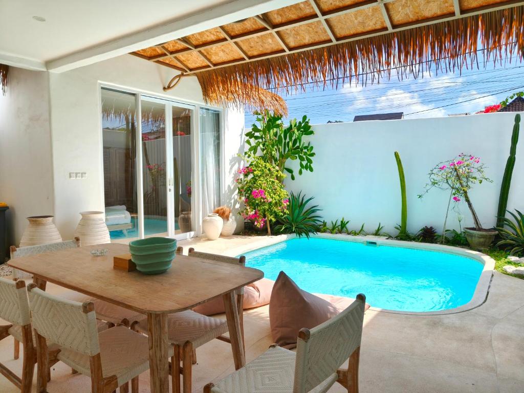 a patio with a table and a swimming pool at Villa Chioni Uluwatu by LODGELINK BALI in Uluwatu