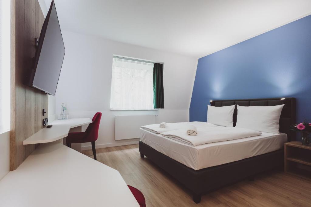 a hotel room with a bed and a desk and a bed at Hotel City Green Hoppegarten in Hoppegarten