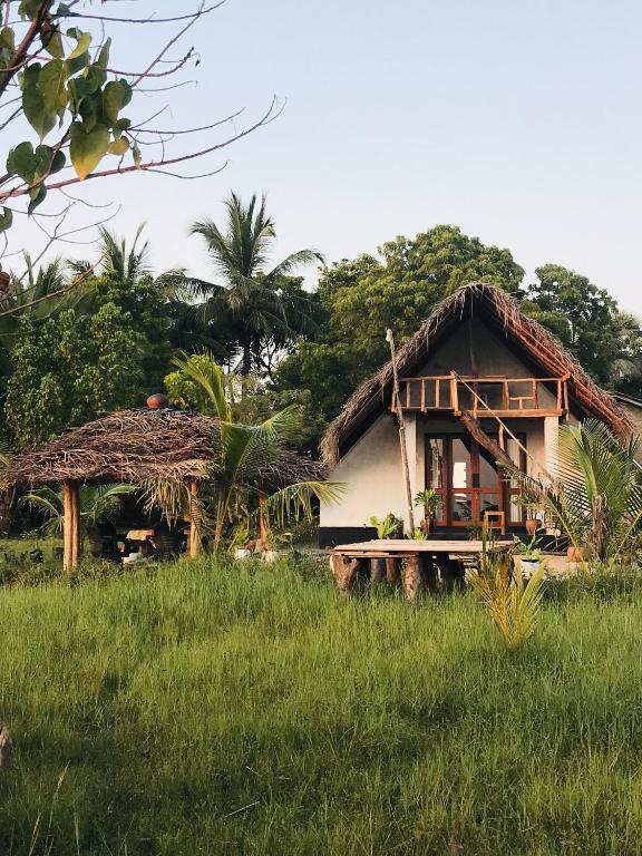a house with a thatched roof in a field at Sambu Cabana Panama in Panama