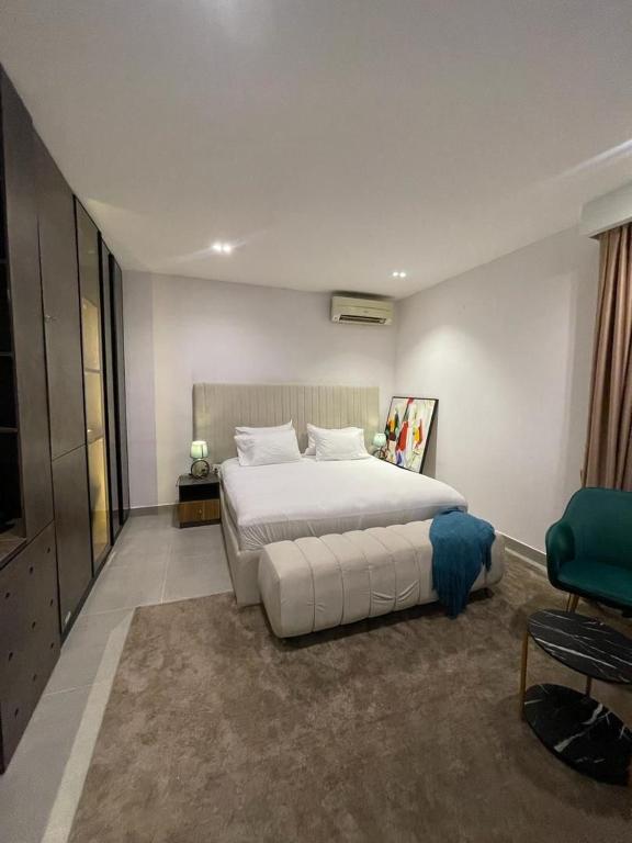 ein Schlafzimmer mit einem großen Bett und einem grünen Stuhl in der Unterkunft Solaris in Lagos