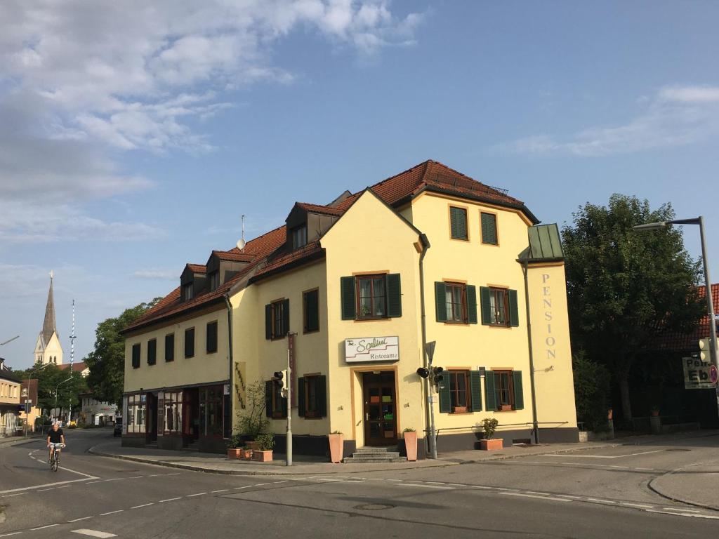 a yellow building on the corner of a street at Eberl Hotel Pension München Feldmoching in Munich