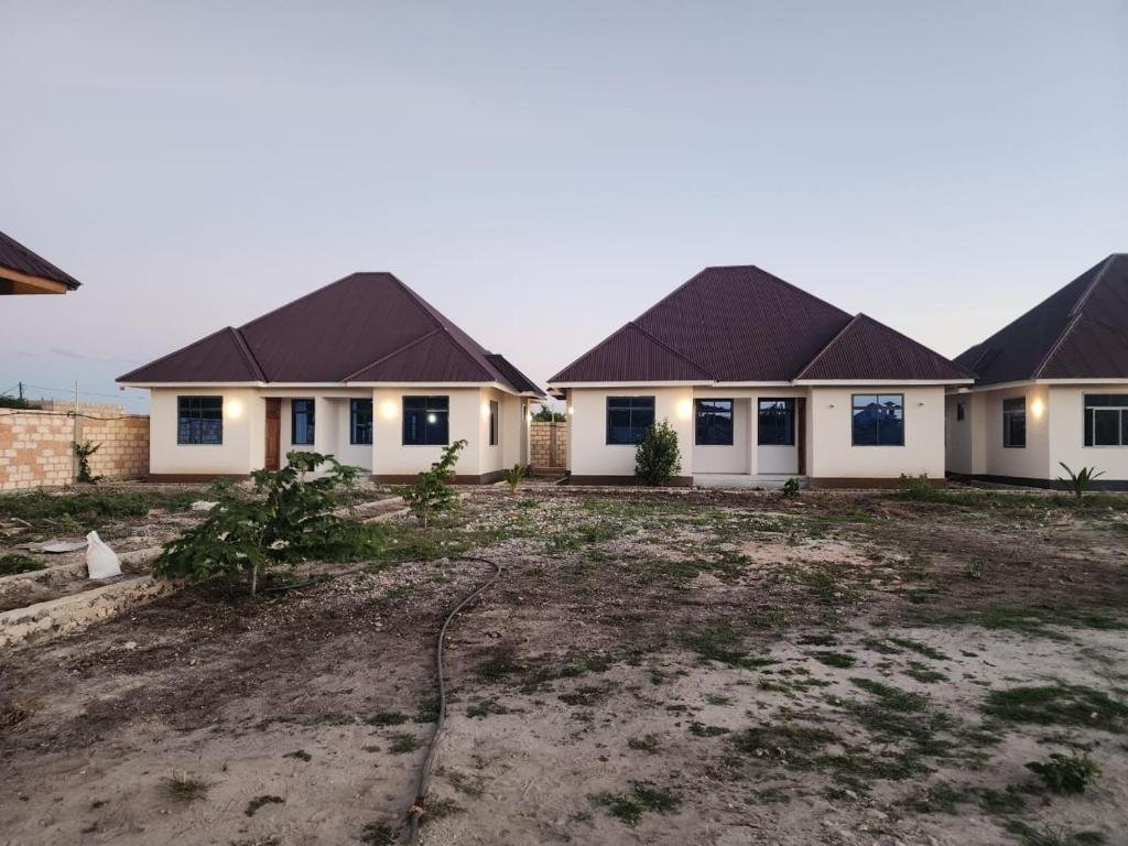 a row of houses in a yard with a driveway at Blue Dhow Villas in Paje
