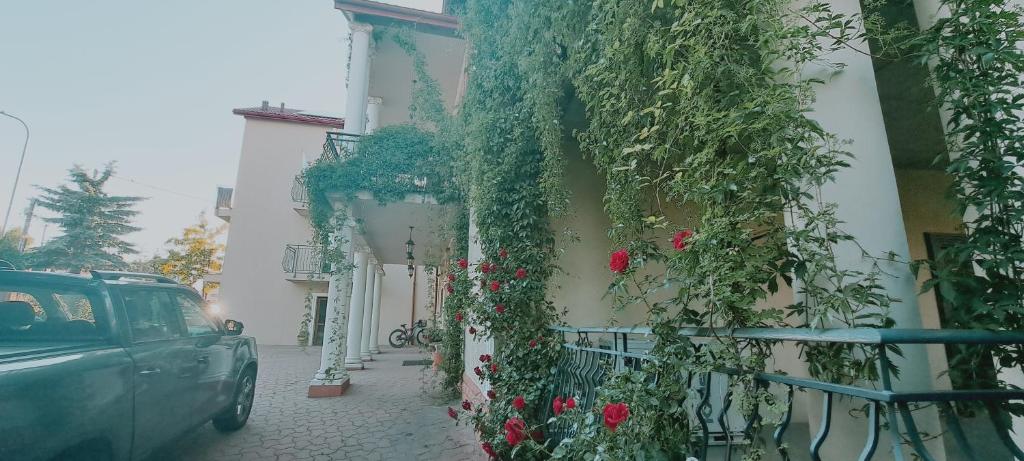 a car parked on a street next to a building with flowers at Hotel i Apartamenty Rosa in Przemyśl