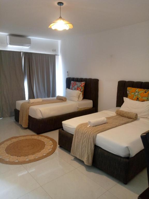 a room with three beds in a room at Natisa Lodge in Livingstone