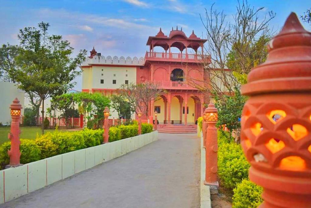 a large red building with a pathway in front of it at Alivaa Heritage Lotwara Fort - Near Shri Mehandipur Balaji Temple in Dausa