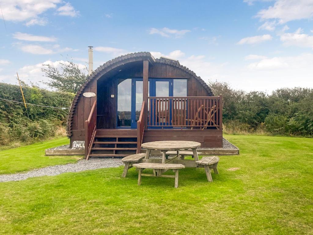 a round cabin with a picnic table and benches in a field at Pencaerau Pods - Enlli Pod in Pwllheli