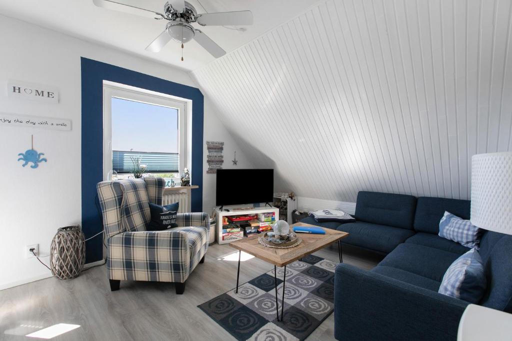 a living room with a blue couch and a chair at Fewo Küstkieker in Böhl