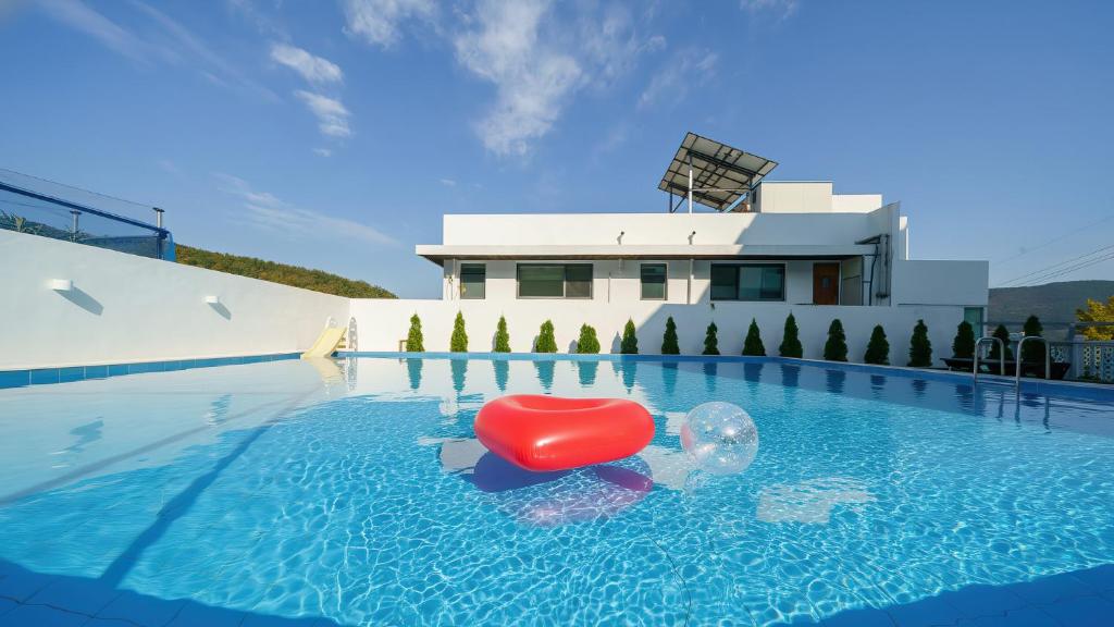 a swimming pool with a red chair in the water at Geoje Forest-Morning Spa Pension in Geoje