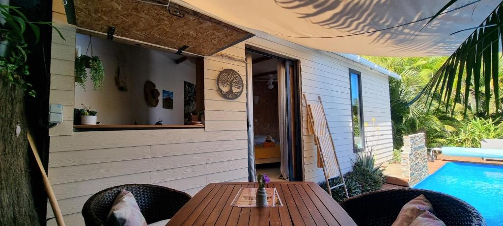 a patio with a table and chairs next to a pool at Bungalow Zananas charme et Authenticité chez l'habitant in Saint-Paul