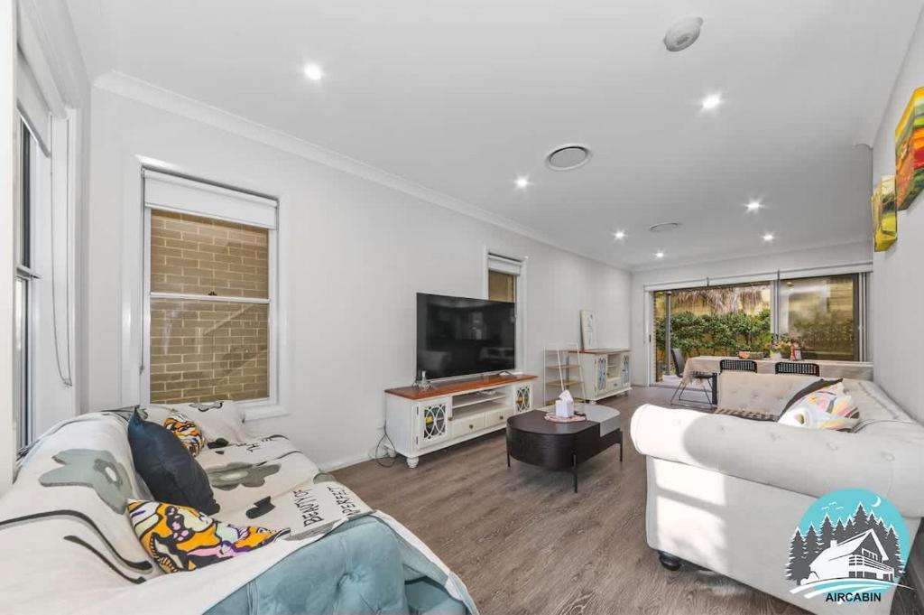 a living room with two couches and a tv at Spacious 4BR Yard Retreat in Kellyville