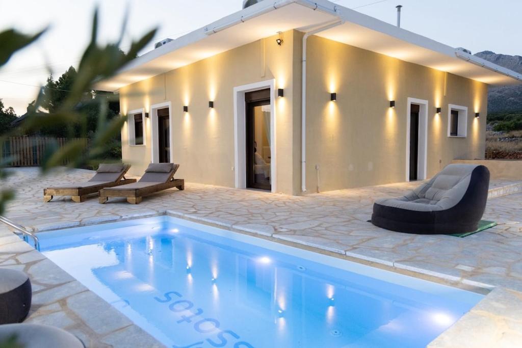 a swimming pool in front of a house at Vakontas Luxury Stay in Gerolimenas